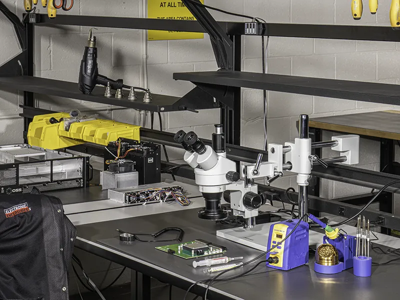 PC board inspection, microscope and soldering rework station on ESD safe work bench.